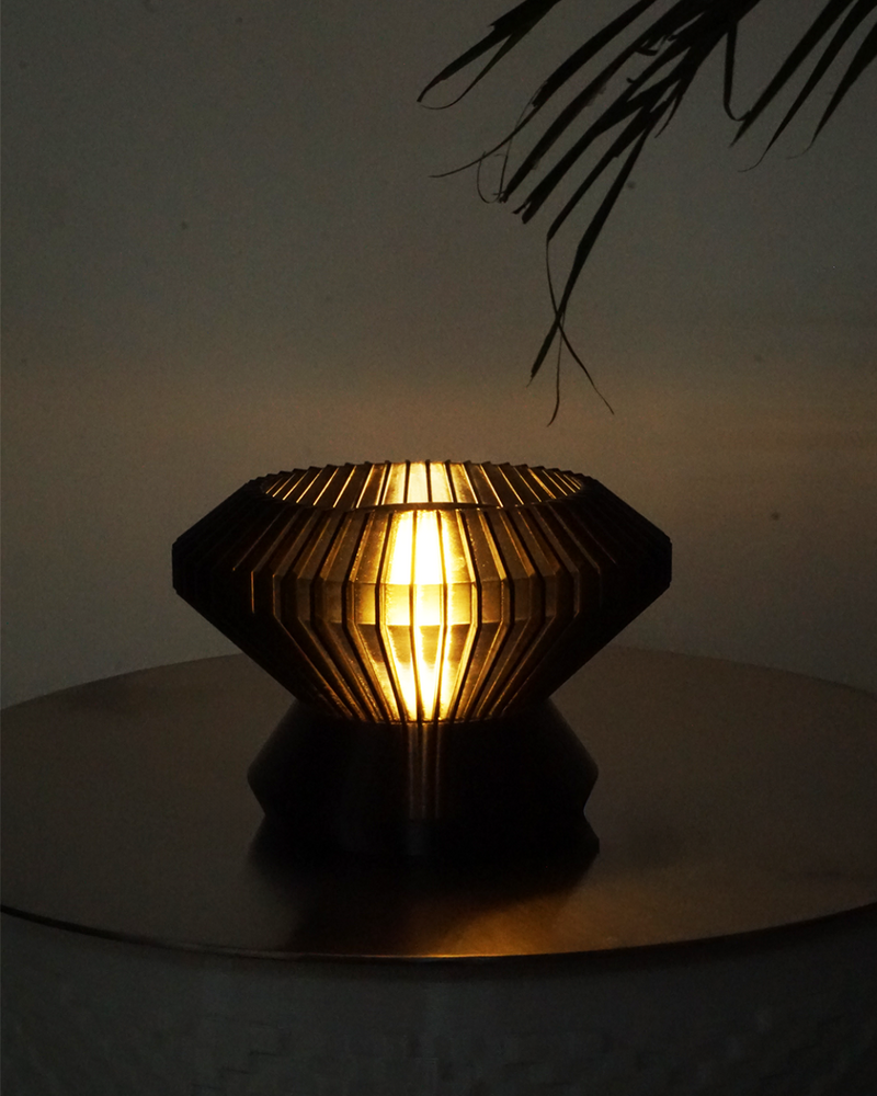 Table lamp with geometric design on a reflective surface against a dark background