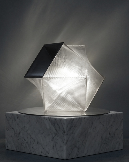 Modern geometric lamp on a marble base against a dark background